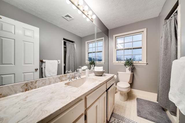 bathroom with tile patterned floors, vanity, toilet, and a textured ceiling