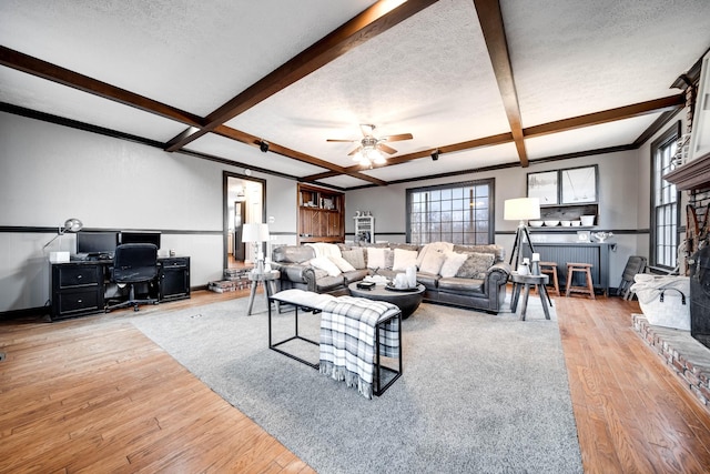 living room featuring ceiling fan, beam ceiling, light hardwood / wood-style floors, and a textured ceiling