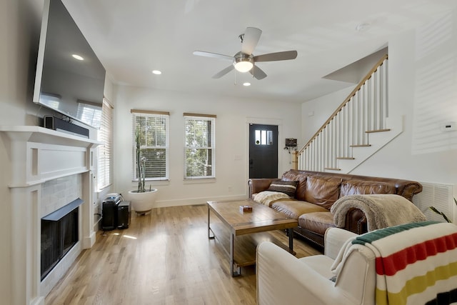 living room with a tiled fireplace, light hardwood / wood-style flooring, and a healthy amount of sunlight