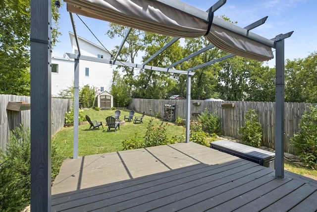 deck with a storage shed, an outdoor fire pit, a yard, and a pergola