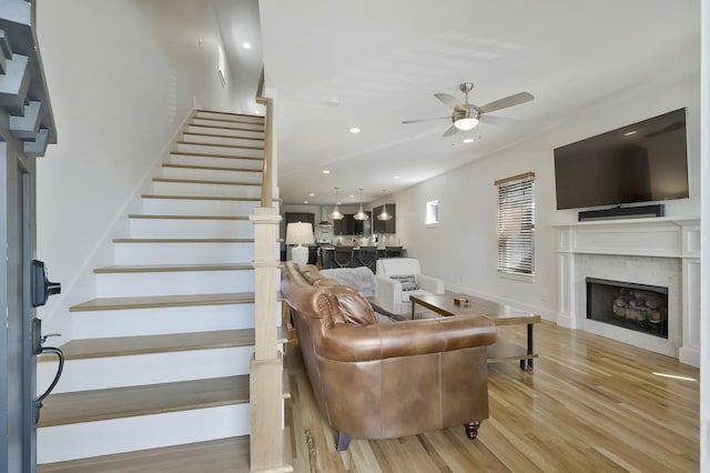 living room featuring ceiling fan, a fireplace, and light wood-type flooring