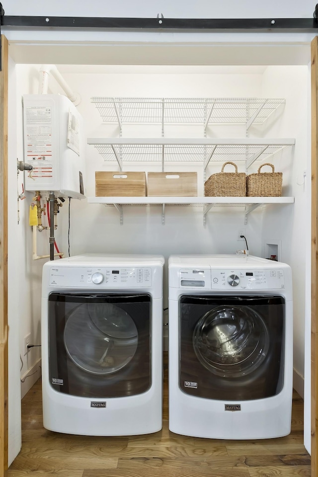 laundry room with water heater, hardwood / wood-style flooring, and washer and dryer