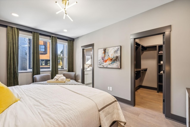 bedroom featuring a spacious closet, ensuite bath, light hardwood / wood-style floors, and a closet