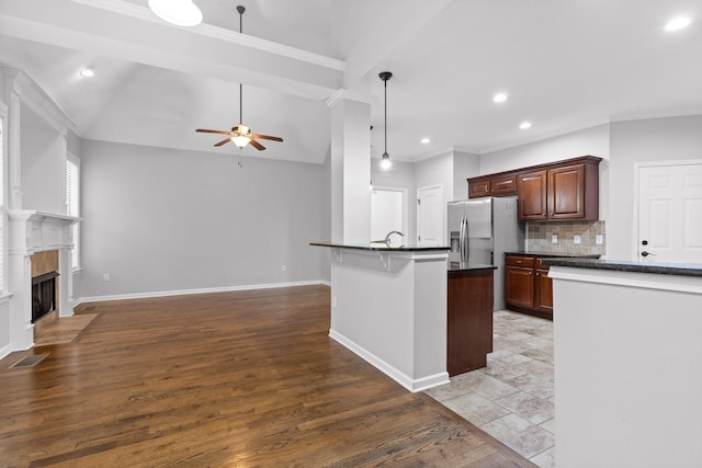 kitchen featuring a breakfast bar, tasteful backsplash, lofted ceiling, hanging light fixtures, and ceiling fan