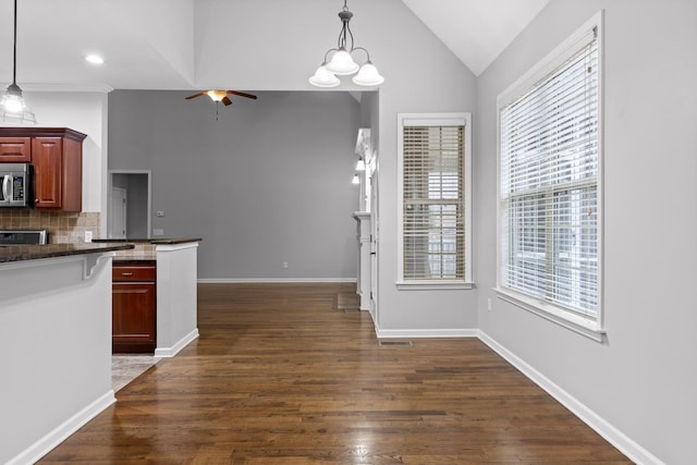 kitchen with hanging light fixtures, a healthy amount of sunlight, dark wood-type flooring, and decorative backsplash