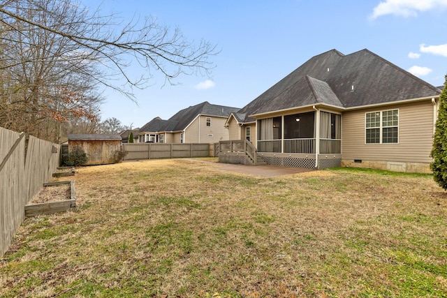 rear view of house with a sunroom, a yard, and a storage unit