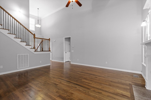 unfurnished living room with dark hardwood / wood-style flooring, ceiling fan, and a high ceiling