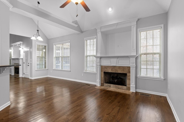 unfurnished living room with lofted ceiling, dark hardwood / wood-style flooring, a tiled fireplace, and a wealth of natural light