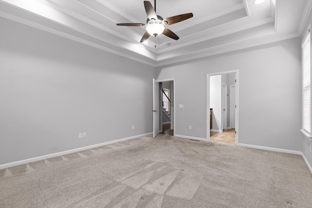 unfurnished bedroom featuring ceiling fan, light colored carpet, ornamental molding, and a tray ceiling