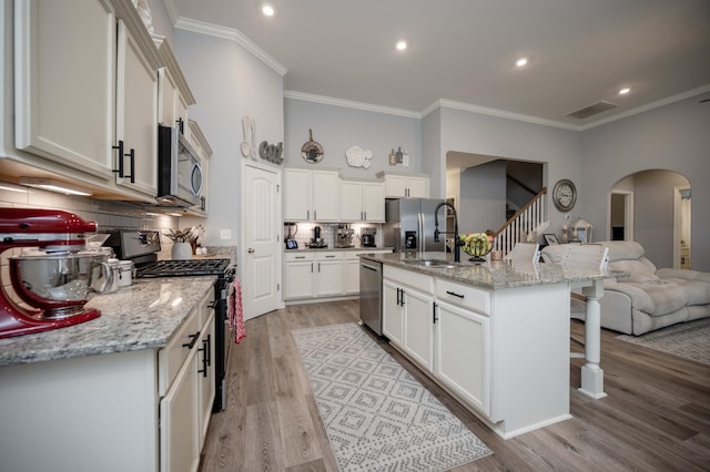 kitchen with appliances with stainless steel finishes, sink, a kitchen island with sink, and white cabinets