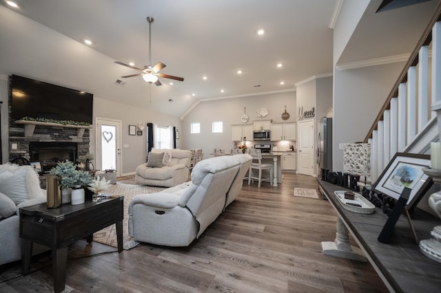 living room with high vaulted ceiling, a fireplace, hardwood / wood-style flooring, ornamental molding, and ceiling fan