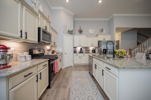 kitchen featuring sink, appliances with stainless steel finishes, light stone countertops, decorative backsplash, and light wood-type flooring