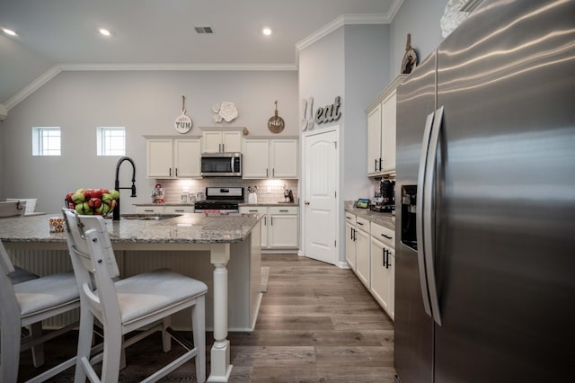 kitchen featuring white cabinetry, sink, a kitchen island with sink, stainless steel appliances, and light stone countertops