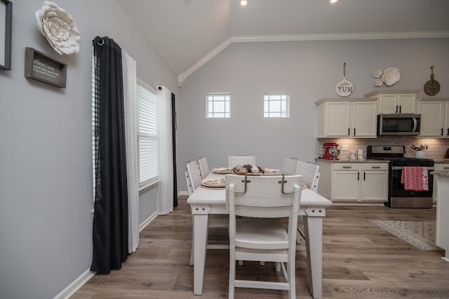 dining room featuring light hardwood / wood-style flooring, vaulted ceiling, and ornamental molding