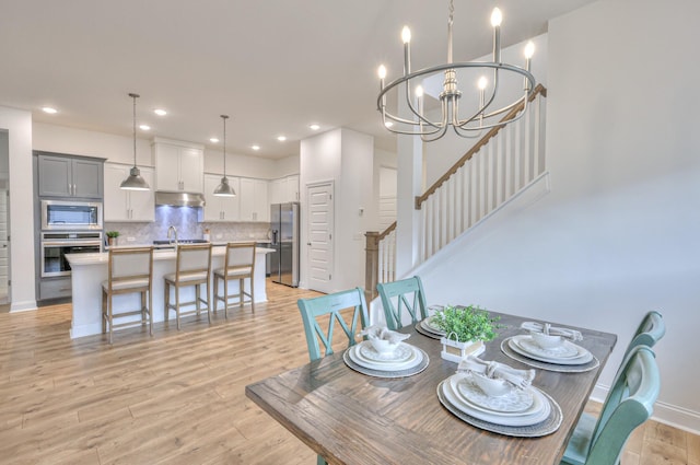 dining area featuring sink, a notable chandelier, and light wood-type flooring