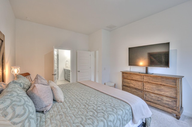 bedroom with light colored carpet and ensuite bath