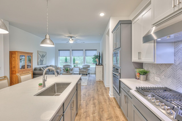 kitchen featuring sink, appliances with stainless steel finishes, gray cabinetry, backsplash, and hanging light fixtures