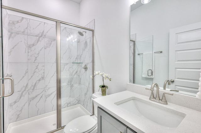 bathroom with vanity, a shower with door, and toilet