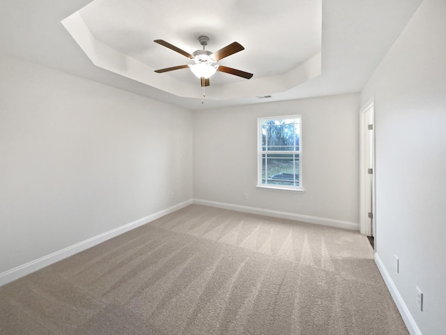 unfurnished room with light carpet, ceiling fan, and a tray ceiling