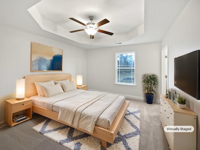 bedroom featuring light carpet, ceiling fan, and a tray ceiling