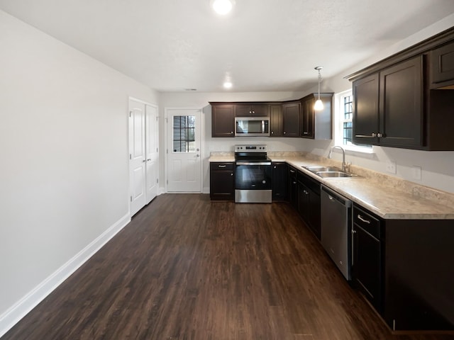 kitchen featuring sink, dark brown cabinets, hanging light fixtures, dark hardwood / wood-style flooring, and stainless steel appliances