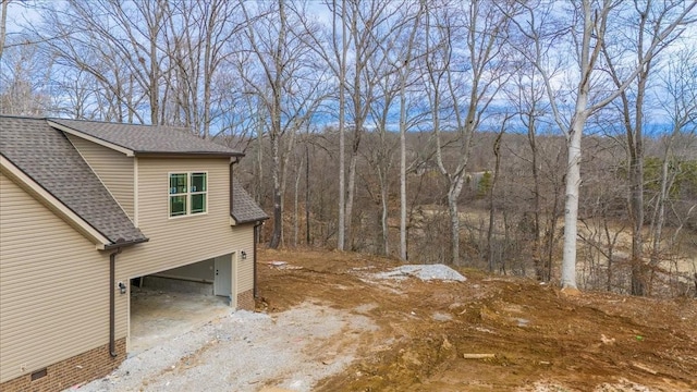 view of side of property featuring a garage, driveway, and a shingled roof