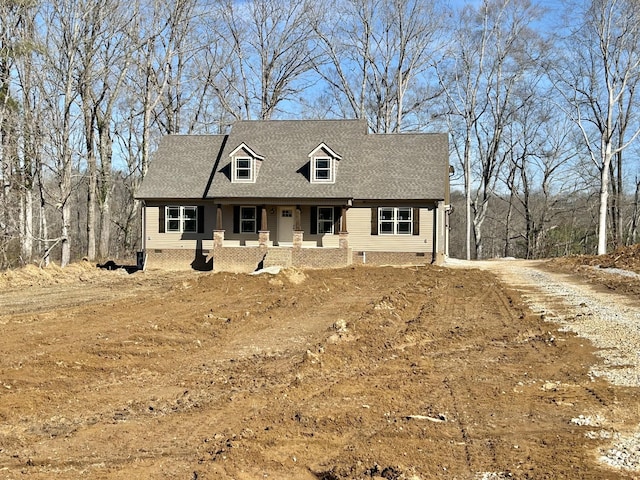 new england style home featuring roof with shingles, covered porch, dirt driveway, and crawl space