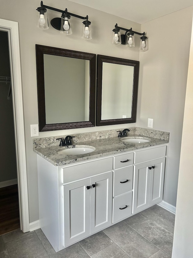 bathroom featuring a sink, baseboards, and double vanity