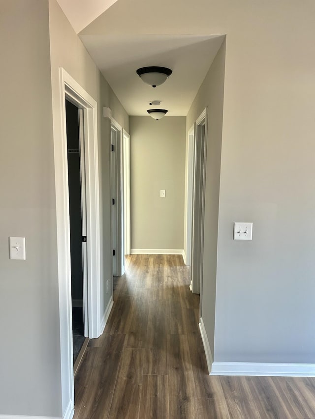 hall featuring dark wood-type flooring and baseboards