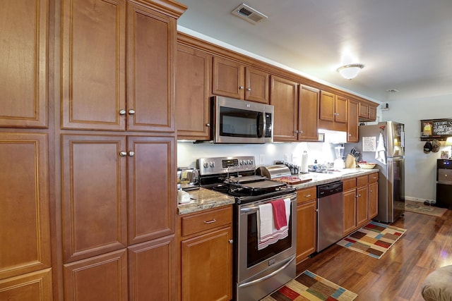 kitchen featuring light stone counters, dark hardwood / wood-style flooring, and stainless steel appliances