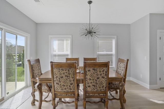 dining space featuring an inviting chandelier, plenty of natural light, and light wood-type flooring