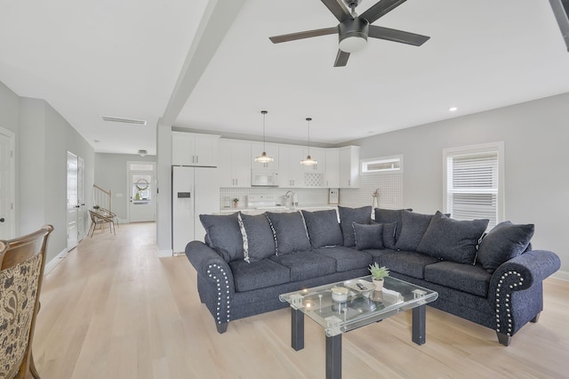 living room featuring ceiling fan, a healthy amount of sunlight, and light wood-type flooring