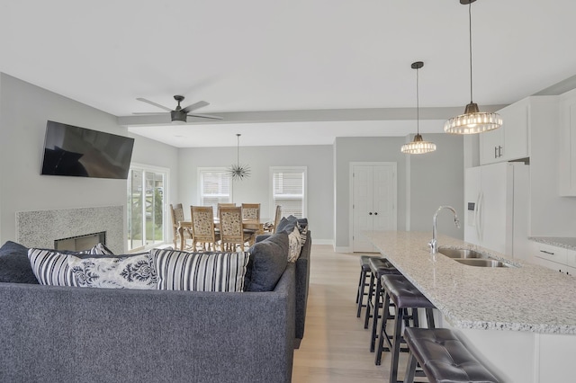 living room with sink, ceiling fan, and light wood-type flooring