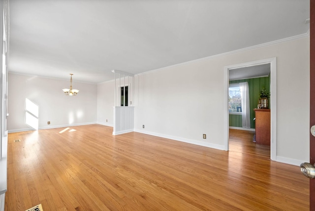 spare room with crown molding, light wood-type flooring, and an inviting chandelier