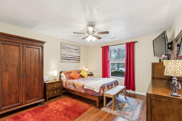 bedroom featuring dark hardwood / wood-style flooring, a textured ceiling, and ceiling fan