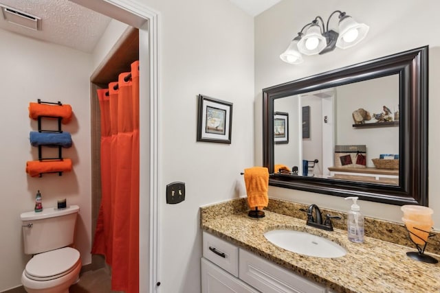 bathroom with vanity, curtained shower, a textured ceiling, and toilet