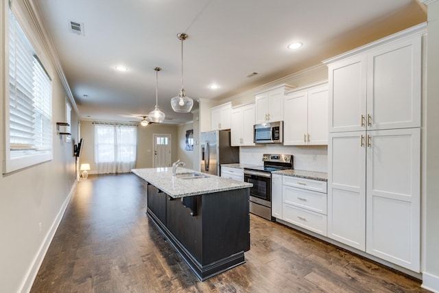 kitchen featuring decorative light fixtures, an island with sink, white cabinets, stainless steel appliances, and light stone countertops