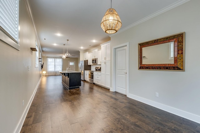 kitchen with stainless steel appliances, hanging light fixtures, a center island with sink, and white cabinets