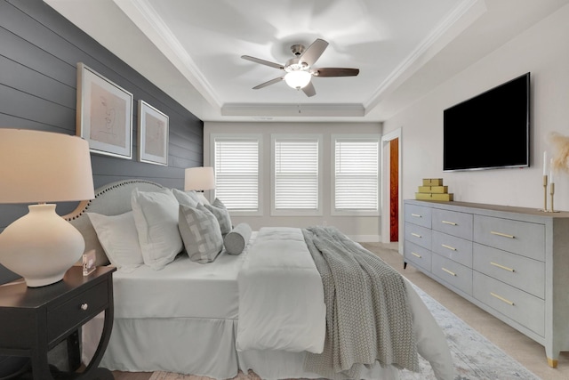 bedroom featuring crown molding, a tray ceiling, light colored carpet, and ceiling fan