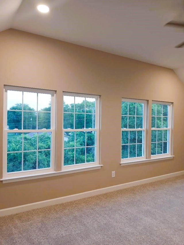 unfurnished room featuring lofted ceiling, carpet floors, and a wealth of natural light