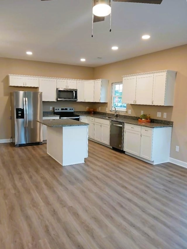 kitchen featuring stainless steel appliances, light hardwood / wood-style floors, a kitchen island, and white cabinets