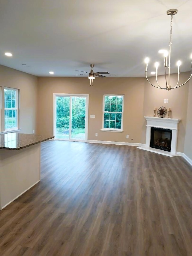 unfurnished living room featuring dark hardwood / wood-style floors and ceiling fan with notable chandelier