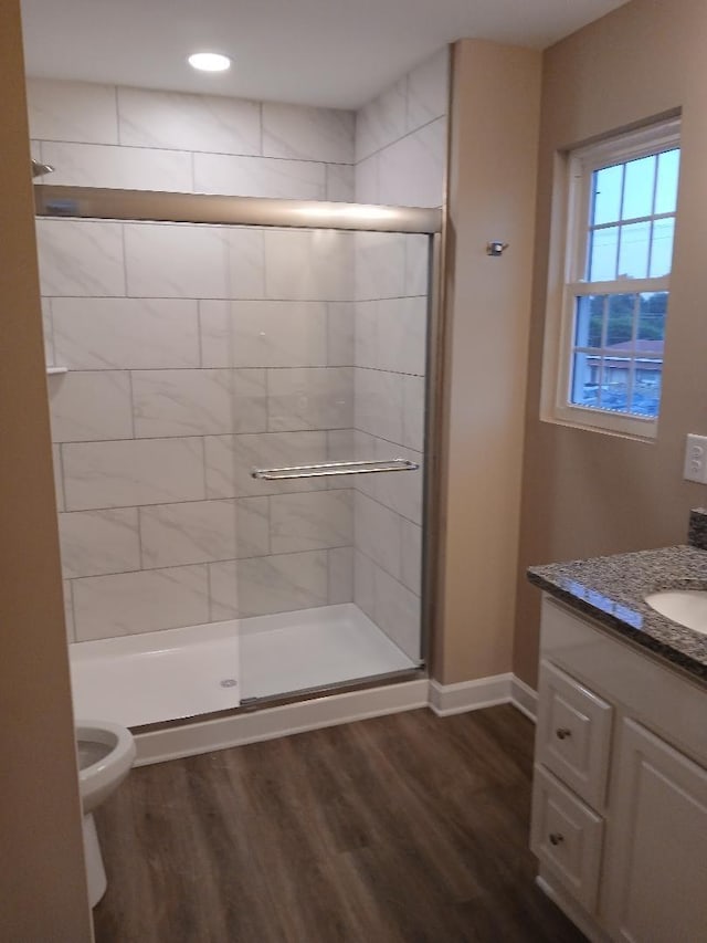 bathroom featuring hardwood / wood-style flooring, vanity, toilet, and a shower with shower door