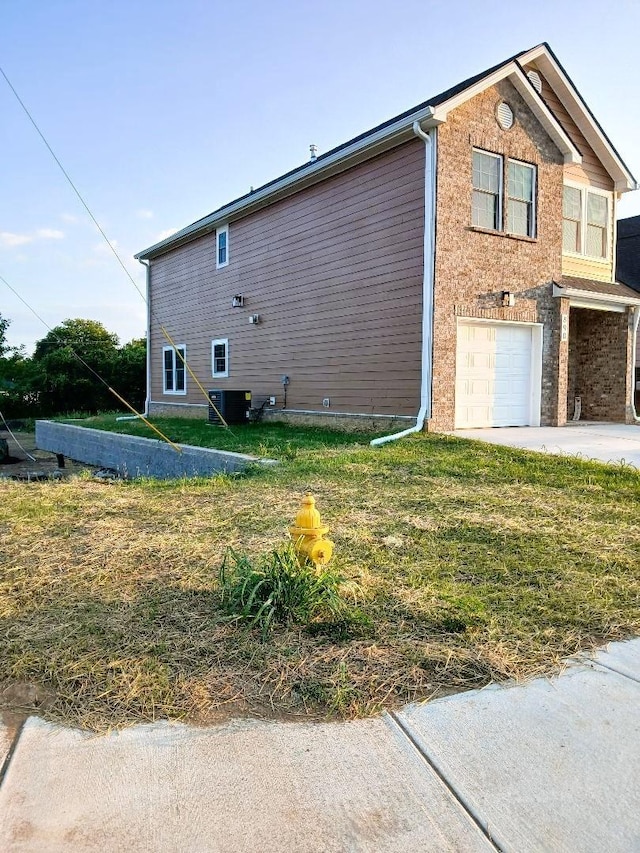 view of side of property with a garage, a yard, and central air condition unit