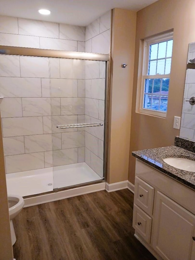 bathroom with vanity, hardwood / wood-style floors, a shower with door, and toilet