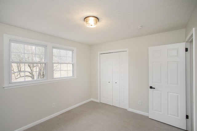 unfurnished bedroom featuring light colored carpet, a textured ceiling, and a closet