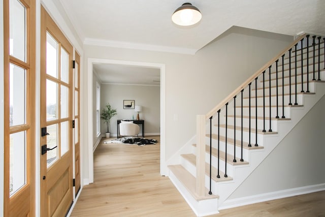 foyer entrance with crown molding and light wood-type flooring