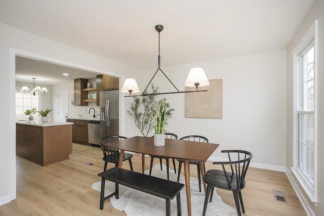 dining area with a wealth of natural light, a chandelier, and light hardwood / wood-style floors