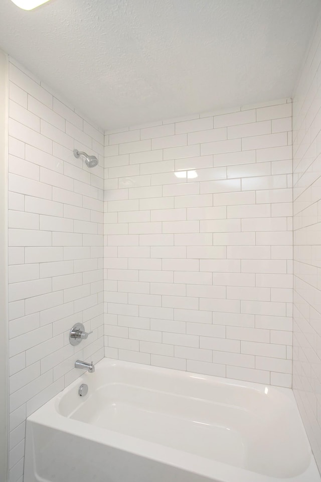 bathroom with tiled shower / bath combo and a textured ceiling