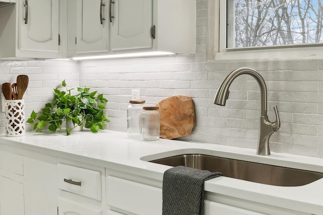 details with white cabinetry, sink, and decorative backsplash